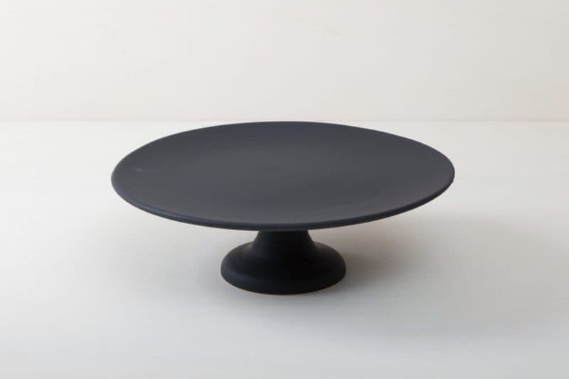  | Our large round elevated cake stand Ernesta rests on a 15 cm high foot and has a diameter of 40 cm. On the matt black serving tray there is enough space to present and arrange cakes, cupcakes, sushi and other delicious food on the table or at the modern buffet. The serving trays are handcrafted from high-quality terracotta and glazed matt black, obviously food safe.These cake stands are available in three different sizes as well as a matt white serving tray. They can be wonderfully combined ... | 